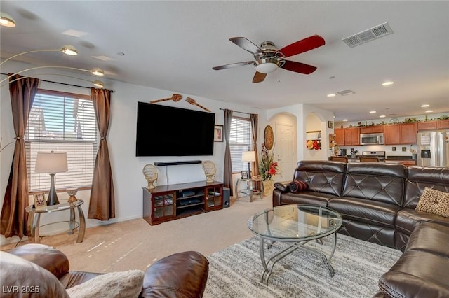 living area featuring visible vents, light carpet, recessed lighting, arched walkways, and ceiling fan