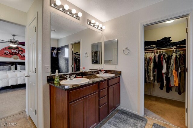 ensuite bathroom with double vanity, connected bathroom, ceiling fan, and a sink