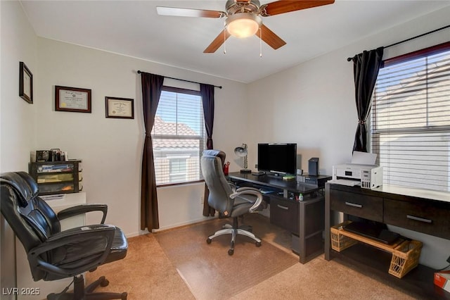 office area featuring baseboards, light carpet, and a ceiling fan