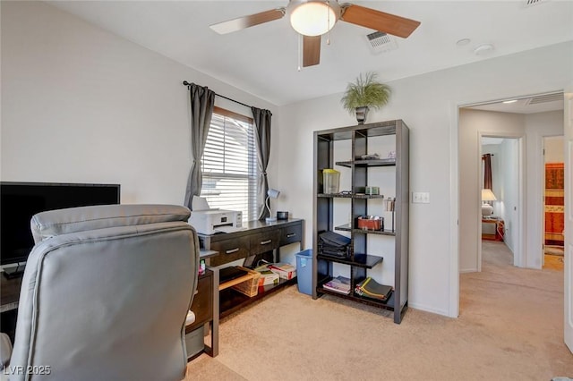 office space featuring visible vents, light colored carpet, baseboards, and a ceiling fan