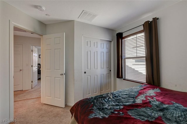 bedroom featuring light carpet, visible vents, and a closet