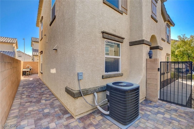 exterior space featuring a patio area, stucco siding, cooling unit, and fence