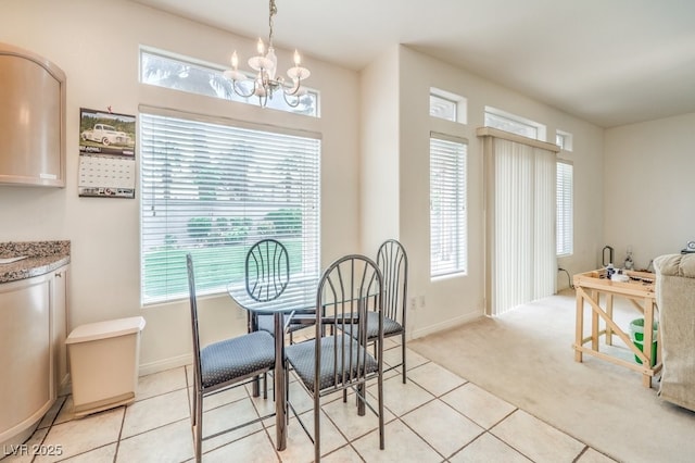 dining space featuring light tile patterned floors, baseboards, light carpet, and a notable chandelier