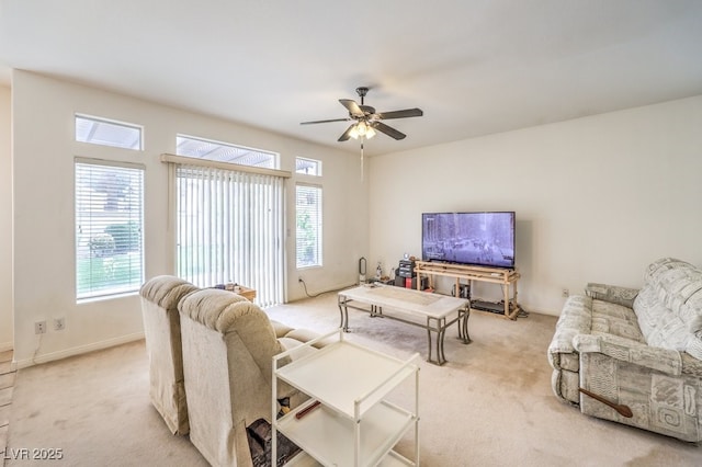 living area with baseboards, light carpet, and a ceiling fan