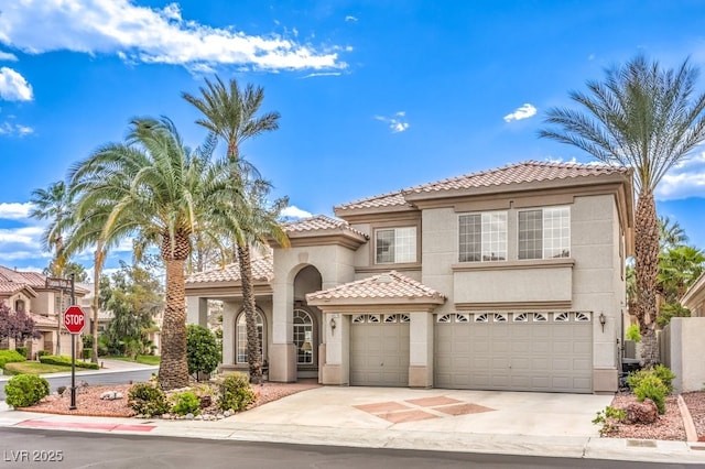 mediterranean / spanish-style house with concrete driveway, a tiled roof, a garage, and stucco siding