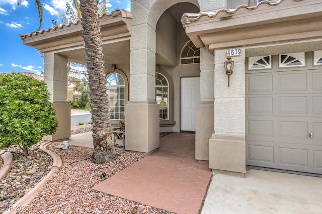 entrance to property featuring a garage and stucco siding