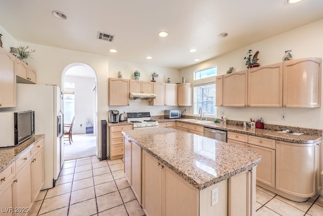 kitchen featuring white appliances, visible vents, arched walkways, a sink, and under cabinet range hood