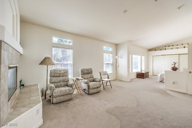 sitting room with a tile fireplace, carpet, and vaulted ceiling