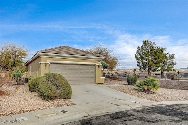 exterior space featuring fence, driveway, stucco siding, a garage, and a tile roof