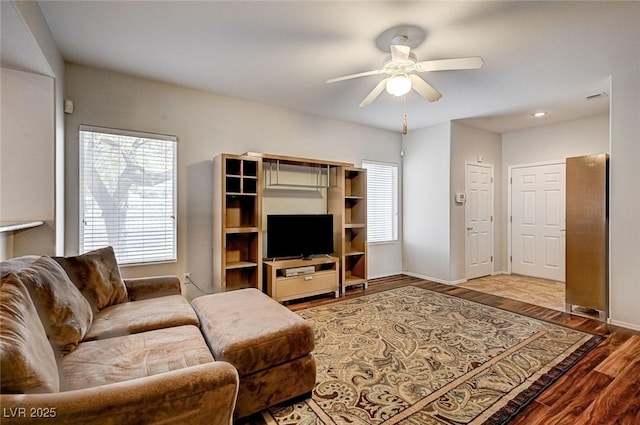 living room featuring baseboards, wood finished floors, and a ceiling fan