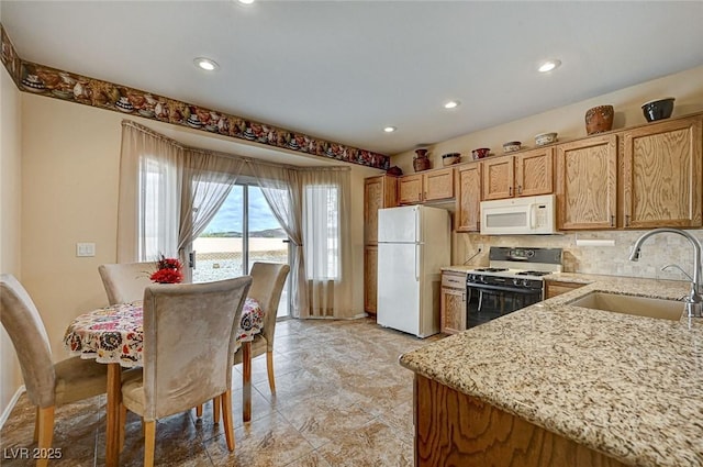 kitchen with a sink, recessed lighting, white appliances, decorative backsplash, and light stone countertops