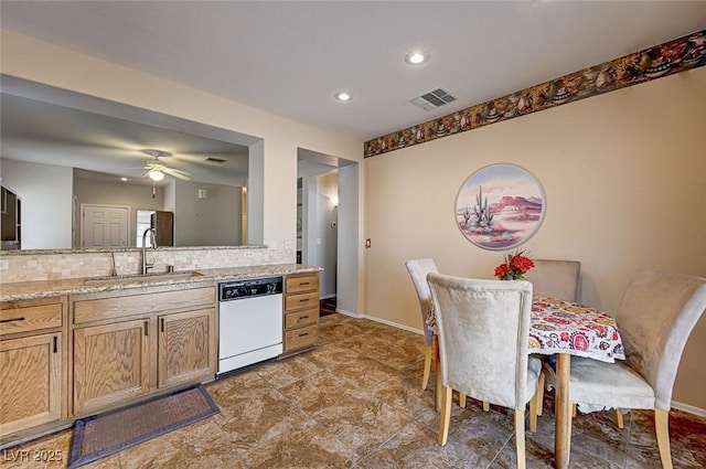 kitchen with baseboards, visible vents, a sink, dishwasher, and backsplash