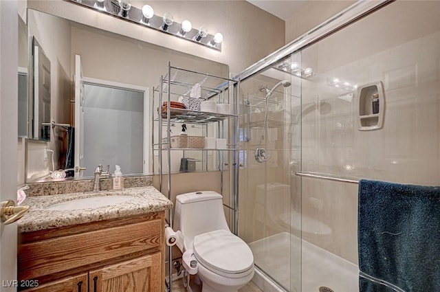 bathroom featuring a shower stall, toilet, and vanity