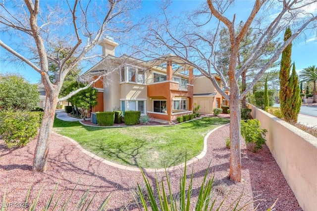 view of front of property featuring fence, a front yard, stucco siding, a chimney, and a balcony