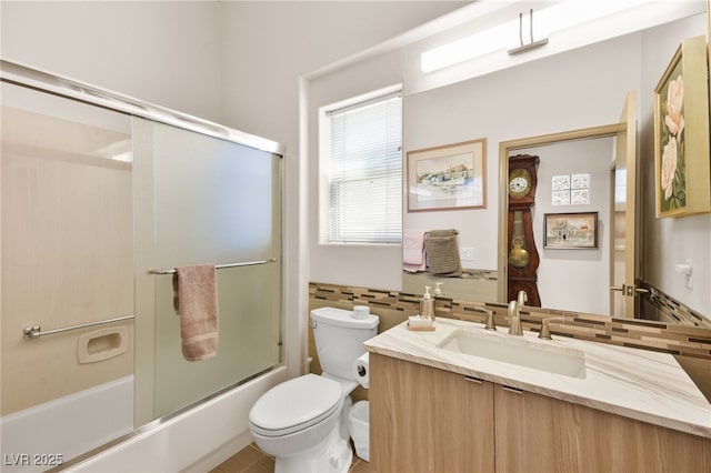 full bath featuring toilet, tile walls, decorative backsplash, enclosed tub / shower combo, and vanity