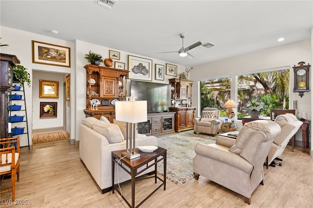 living room with visible vents, light wood-style flooring, and ceiling fan