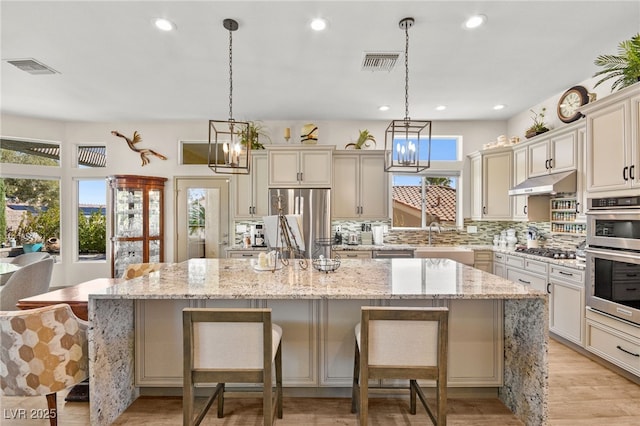 kitchen with under cabinet range hood, plenty of natural light, visible vents, and appliances with stainless steel finishes