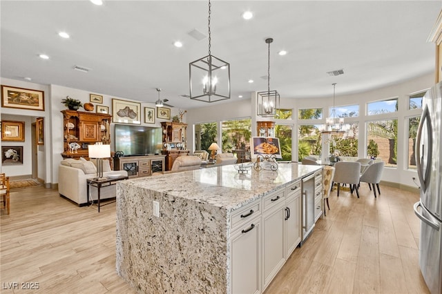 kitchen with visible vents, white cabinetry, freestanding refrigerator, light wood-style floors, and light stone countertops