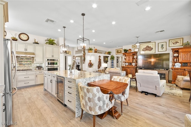 kitchen with wine cooler, open floor plan, appliances with stainless steel finishes, and visible vents