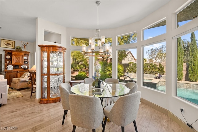 dining space with a notable chandelier, baseboards, and light wood-type flooring