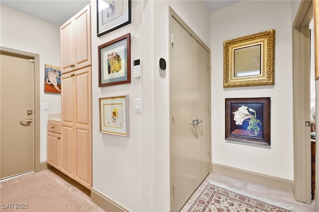 hall with light wood-style flooring and baseboards