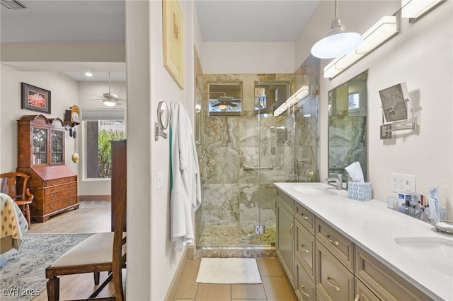 bathroom with ceiling fan, double vanity, a marble finish shower, and a sink