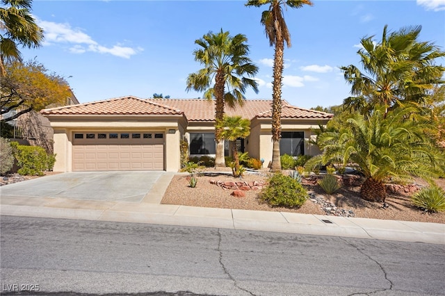 mediterranean / spanish house featuring a tiled roof, a garage, driveway, and stucco siding