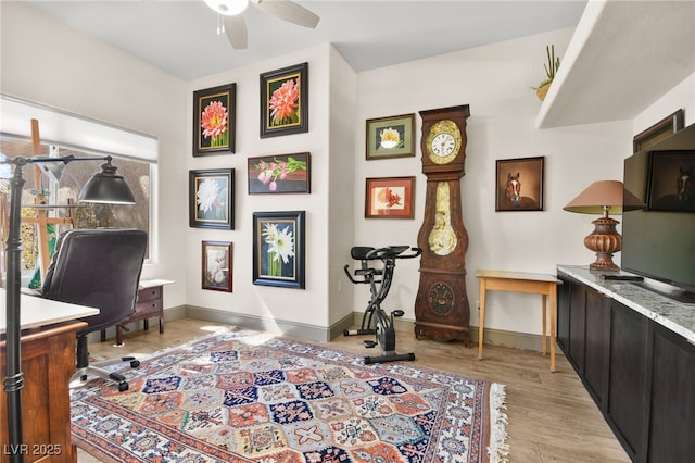 home office with baseboards, a ceiling fan, and light wood finished floors