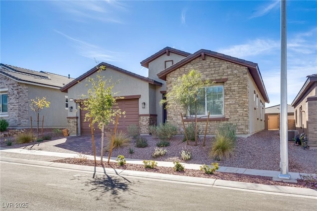 view of front of home with stucco siding, decorative driveway, stone siding, central AC, and a garage