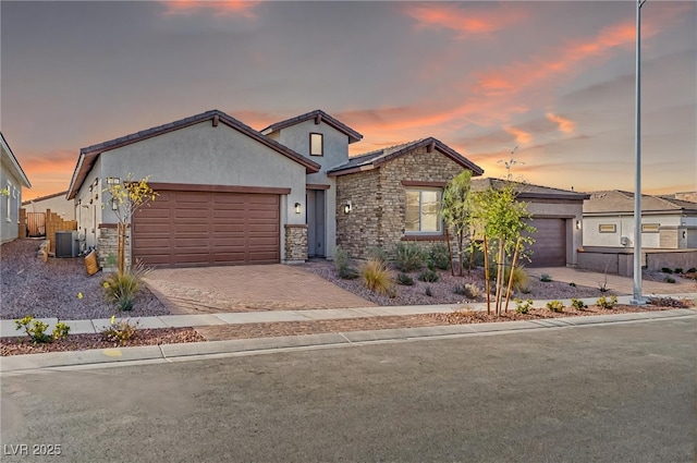 view of front of home featuring stone siding, decorative driveway, and a garage