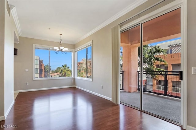 unfurnished room featuring a notable chandelier, crown molding, baseboards, and wood finished floors