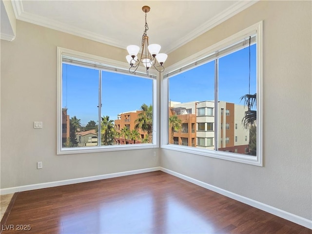 unfurnished room featuring wood finished floors, baseboards, a chandelier, and ornamental molding