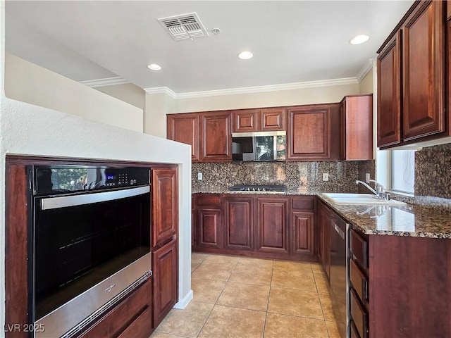 kitchen with visible vents, a sink, appliances with stainless steel finishes, crown molding, and backsplash