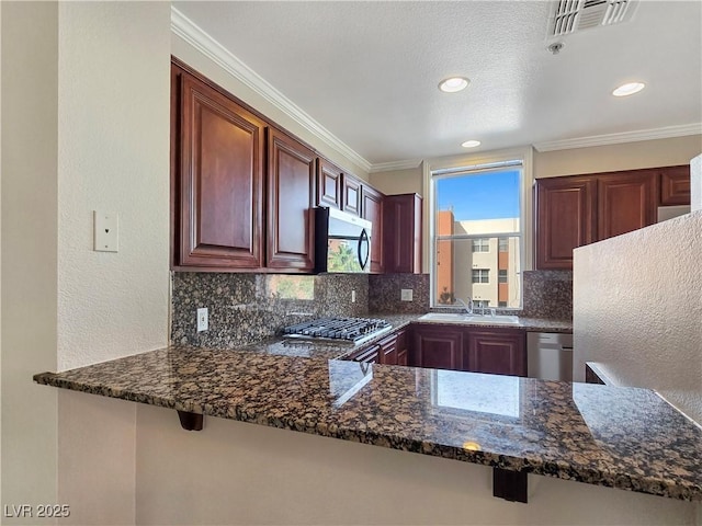 kitchen with visible vents, a sink, appliances with stainless steel finishes, crown molding, and decorative backsplash