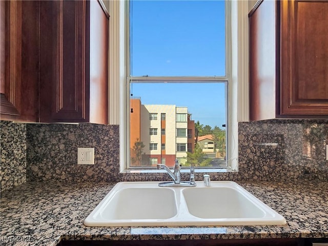 kitchen with decorative backsplash, dark brown cabinets, and a sink