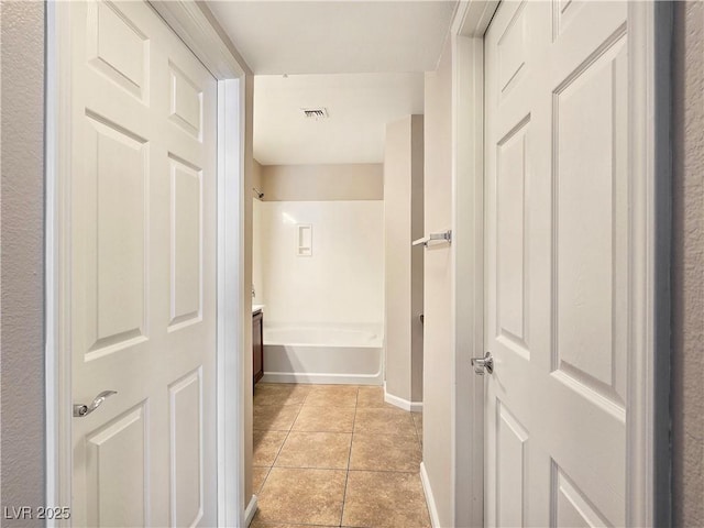 hallway with light tile patterned floors, visible vents, and baseboards