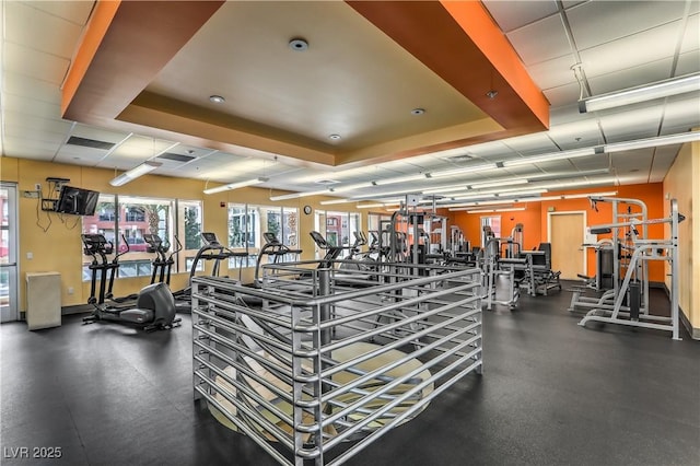 exercise room with a tray ceiling and visible vents