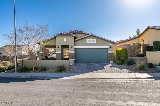 mediterranean / spanish-style home featuring stucco siding, a garage, stone siding, a tiled roof, and decorative driveway