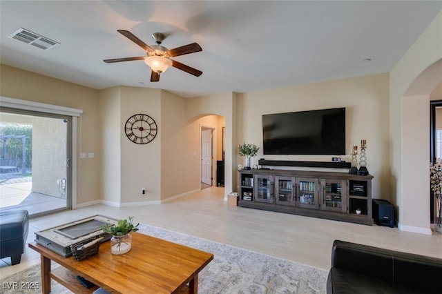 living area with arched walkways, visible vents, baseboards, and a ceiling fan