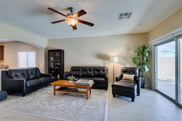 living area featuring arched walkways, visible vents, ceiling fan, and light tile patterned floors