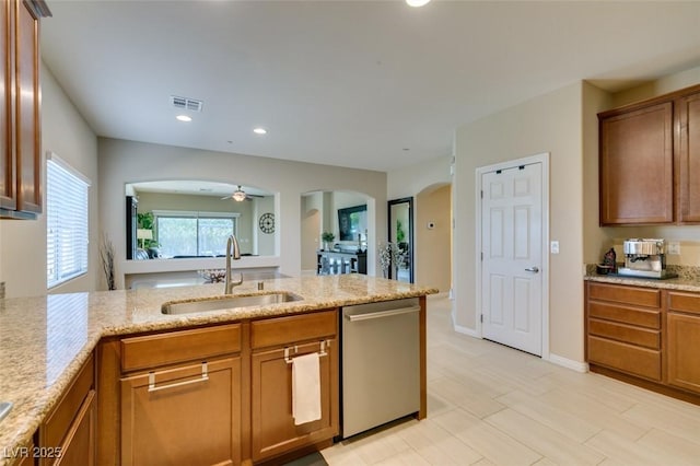 kitchen with light stone counters, visible vents, arched walkways, a sink, and stainless steel dishwasher