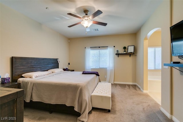 carpeted bedroom with visible vents, arched walkways, baseboards, and ceiling fan