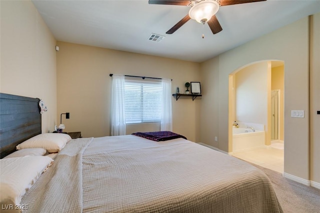 bedroom featuring carpet, visible vents, arched walkways, ceiling fan, and ensuite bathroom