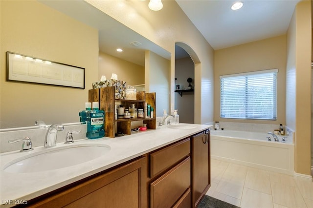 bathroom featuring tile patterned flooring, a garden tub, double vanity, and a sink