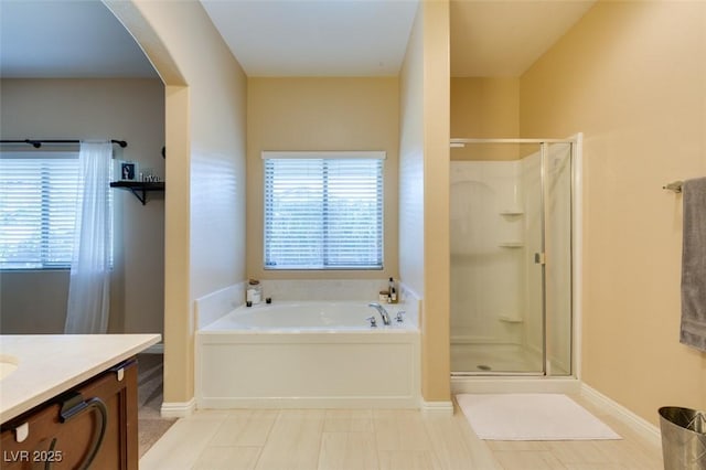 bathroom featuring baseboards, a shower stall, vanity, and a garden tub