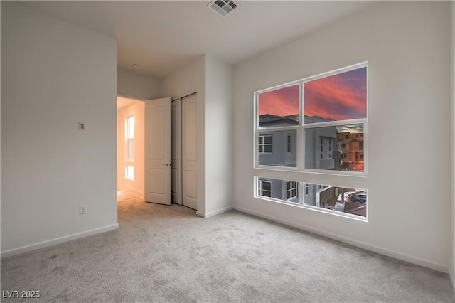 carpeted spare room with visible vents, baseboards, and a healthy amount of sunlight