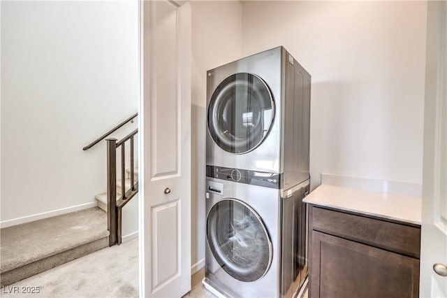 washroom featuring light carpet, cabinet space, stacked washer and clothes dryer, and baseboards