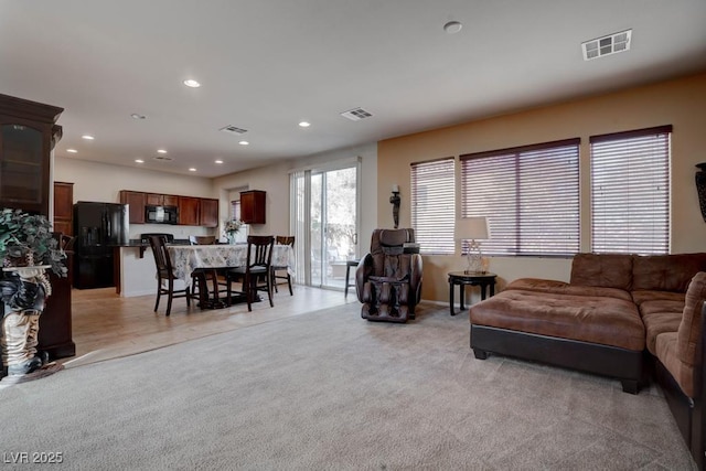 living area with recessed lighting, light colored carpet, and visible vents