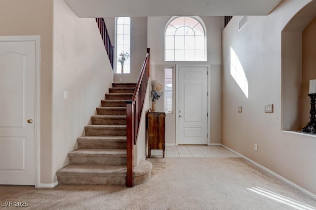 foyer entrance with carpet flooring, baseboards, stairs, and visible vents