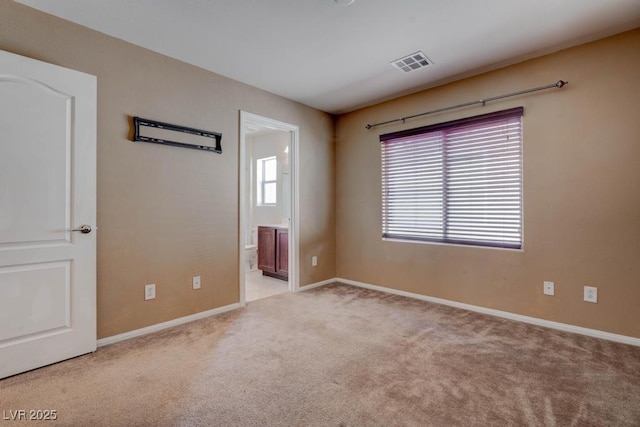 empty room featuring a wealth of natural light, visible vents, baseboards, and carpet